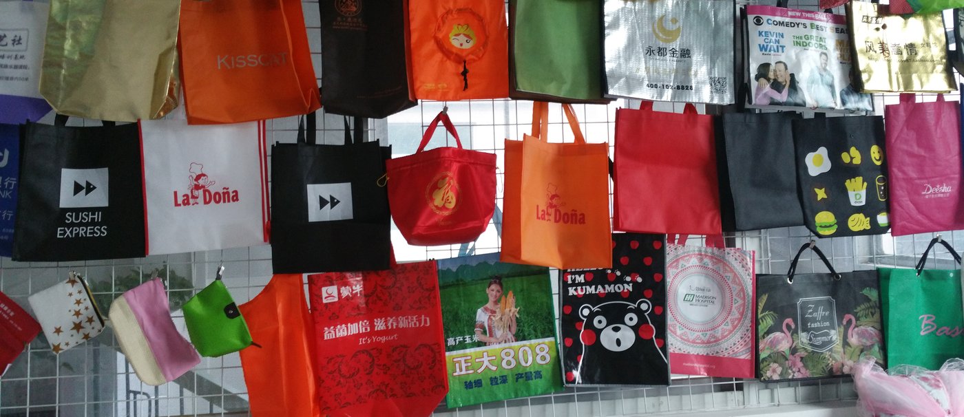 Wall of custom-printed branded shopping bags produced by Genesis Bags